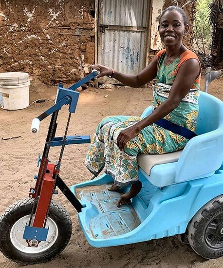 A younger women sitting in a blue mobility cart with a big smile on her face.